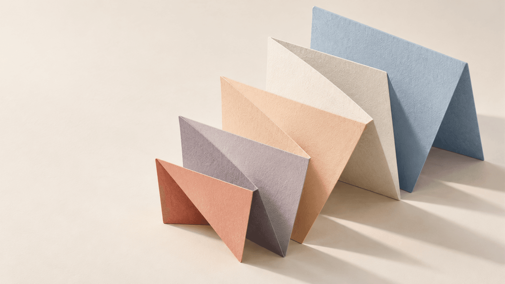 Five folded sculptural planes in muted coral, lavender, cream, peach, and blue; abstract artwork.